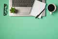 Top view photo of flowerpot pen and planner on grey laptop keyboard glasses and cup of coffee on isolated turquoise background