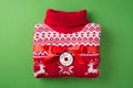 Top view photo of folded red and white christmas sweater with red ribbon bow and label with inscription merry christmas on