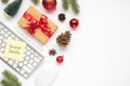 Top view photo of giftbox with red bow sticker note paper on keyboard computer mouse pen red christmas tree balls fir toy pine Royalty Free Stock Photo