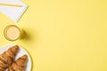 Top view photo of glass of juice plate with fresh croissants and yellow pencil on small notebook on isolated pastel yellow