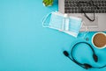 Top view photo of glasses two medical facemasks sanitizer bottle on laptop binder clip headphones plant and cup of drink on