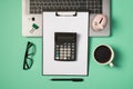 Top view photo of green and black binder clips piggy bank on grey laptop glasses cup of drink pen and calculator on black Royalty Free Stock Photo