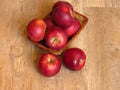 Juicy red organic apples in a basket on oak tree wood background. Autumn Fall season orchard harvest production. Royalty Free Stock Photo