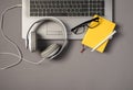 Top view photo of laptop keyboard wired white headphones glasses pen and yellow reminder on isolated grey background Royalty Free Stock Photo