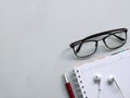 Top view photo of note book,pen,earphone and eye glasses isolated on white background. Royalty Free Stock Photo