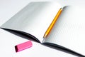 Top view photo of a notebook with checkered pages, with a yellow pencil and a pink eraser lying on it Royalty Free Stock Photo