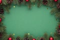 Top view photo of pine branches with cones red christmas tree balls and gold stars confetti on isolated green background with Royalty Free Stock Photo