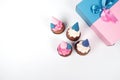 Top view photo of pink and blue cupcakes, party hats, and gift boxes