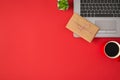 Top view photo of rectangular craft paper giftbox with twine bow on grey laptop flowerpot and cup of coffee on isolated red Royalty Free Stock Photo