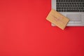 Top view photo of rectangular craft paper giftbox with twine bow on grey laptop on isolated red background with copyspace Royalty Free Stock Photo