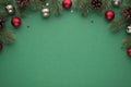 Top view photo of red and silver christmas tree balls on pine branches with cones and stars confetti on isolated green background Royalty Free Stock Photo