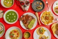 Top view photo of a red table in a Mexican restaurant with carnitas, tacos al pastor, red grasshoppers, nachos with guacamole and Royalty Free Stock Photo