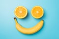 Top view photo of smiling face made from two orange halves and yellow banana on isolated pastel blue background Royalty Free Stock Photo