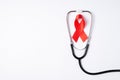 Top view photo of stethoscope and red ribbon symbol of aids awareness on isolated white background with empty space