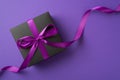 Top view photo of stylish black giftbox with violet satin ribbon bow on isolated violet background with blank space Royalty Free Stock Photo