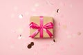 Top view photo of stylish craft paper giftbox with pink ribbon bow and large shiny sequins on isolated pastel pink background Royalty Free Stock Photo