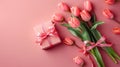 Top view photo of stylish pink gift box with ribbon bow and bouquet of tulips isolated on pastel pink background. Royalty Free Stock Photo