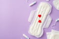 Top view photo of tampons and sanitary napkin with red hearts on isolated pastel lilac background with copyspace Royalty Free Stock Photo