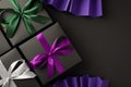 Top view photo of three black gift boxes with violet green and white ribbon bows and violet paper fans on isolated black Royalty Free Stock Photo