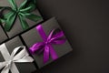 Top view photo of three stylish black gift boxes with purple green and white satin ribbon bows on isolated black background with Royalty Free Stock Photo