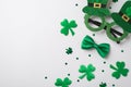 Top view photo of the tinsel Irish glasses with hats silk green bow tie and green confetti different size in shape of clovers and