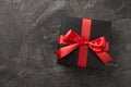 Top view photo of valentine`s day decorations black giftbox with red silk ribbon bow on isolated textured dark grey concrete Royalty Free Stock Photo