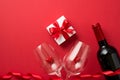 Top view photo of valentine`s day decorations giftbox with bow red curly ribbon small hearts in two wineglasses and wine bottle o Royalty Free Stock Photo