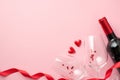 Top view photo of valentine`s day decorations red curly ribbon small hearts between two wineglasses with confetti and wine bottle Royalty Free Stock Photo