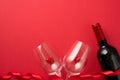 Top view photo of valentine`s day decorations red curly ribbon small hearts in two wineglasses and wine bottle on isolated red Royalty Free Stock Photo