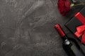 Top view photo of valentine`s day decorations wine bottle black giftbox with red bow and red rose on isolated textured dark grey Royalty Free Stock Photo