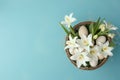 Top view photo of a vase filled with white lilies, a basket with painted Easter eggs