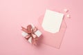 Top view photo of white giftbox with pink satin ribbon bow small hearts and open pink envelope with paper card on isolated pastel Royalty Free Stock Photo