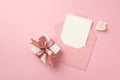 Top view photo of white giftbox with pink silk ribbon bow decorative heart and open pink envelope with card on isolated pastel Royalty Free Stock Photo