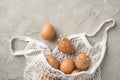 Top view photo of white string bag with brown eggs decorated by gypsophila flowers and twine on isolated grey concrete background Royalty Free Stock Photo