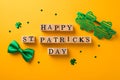 Top view photo of wooden cubes labeled happy st patricks day shamrock shaped party glasses green bow-tie and clover shaped