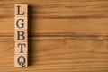 Top view photo of wooden cubes labeled LGBTQ on wooden background with copyspace