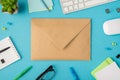 Top view photo of workplace with chancellery keyboard mouse glasses plant and closed paper envelope in the middle on isolated blue