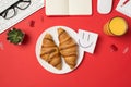 Top view photo of workplace keyboard mouse stationery glasses plant notebooks glass of juice plate with two fresh croissants and