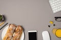 Top view photo of workspace keyboard mouse glasses binder clips glass of orange juice smartphone plate with two sandwiches pencils Royalty Free Stock Photo