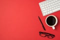 Top view photo of workspace white keyboard pen glasses and cup of coffee on isolated red background with empty space Royalty Free Stock Photo