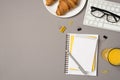 Top view photo of workstation glass of juice plate with croissants glasses on keyboard stationery binder clips and pen on stack of