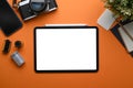 Top view of photographer workplace with tablet, camera, coffee cup and notebook on orange background. Royalty Free Stock Photo