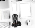 Top view of photographer workplace: Keyboard, tablet, camera and smartphone on white desk background