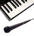 Top view of piano keyboard and black vocal microphone on white background closeup