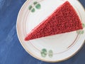 Top view piece of red velvet cake in soft brown plate on black stone background.