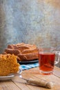 Top view of piece of yogurt sponge cake on plate with fork, glass with rooibos tea, on rustic table,