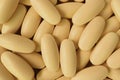 Top view of pile of creamy yellow oval shaped pills for background or banner