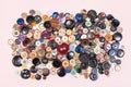 Top view of pile of many various buttons on pink