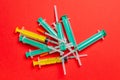Top view of a pile of medical syringes and insulin syringes with needles at red background with copy space. Injection treatment