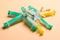 Top view of a pile of medical syringes and insulin syringes with needles at orange background with copy space. Injection